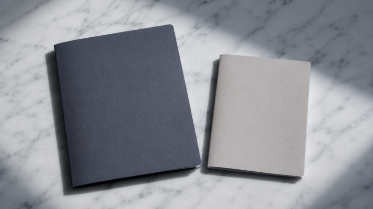 회색 대리석 위에 나란히 놓인 짙은 남색과 밝은 베이지색 연금계좌 서류철